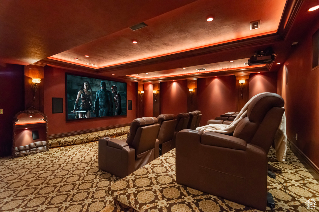 Carpeted home theater room featuring a raised ceiling, baseboards, ornamental molding, and recessed lighting