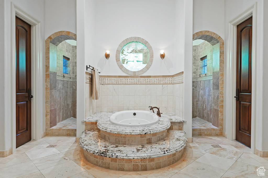 Bathroom with a whirlpool tub, a walk in shower, marble finish flooring, and baseboards