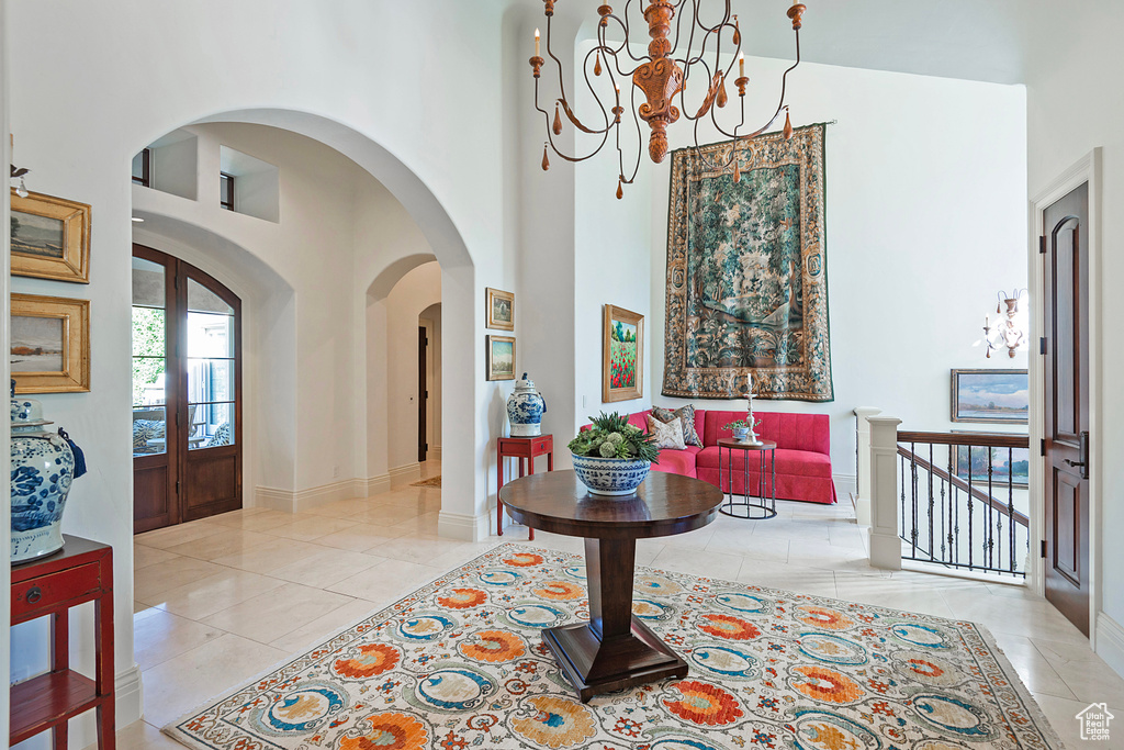 Foyer entrance featuring a high ceiling, light tile patterned floors, a chandelier, baseboards, and arched walkways