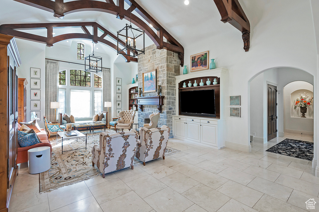 Living room with high vaulted ceiling, a chandelier, beamed ceiling, arched walkways, and a fireplace