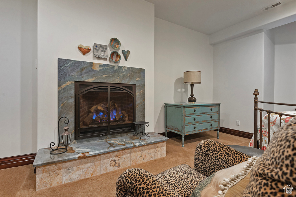 Carpeted living area featuring a premium fireplace and baseboards