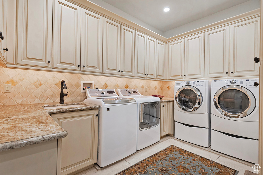 Laundry area featuring washer and dryer, light tile patterned flooring, and cabinet space