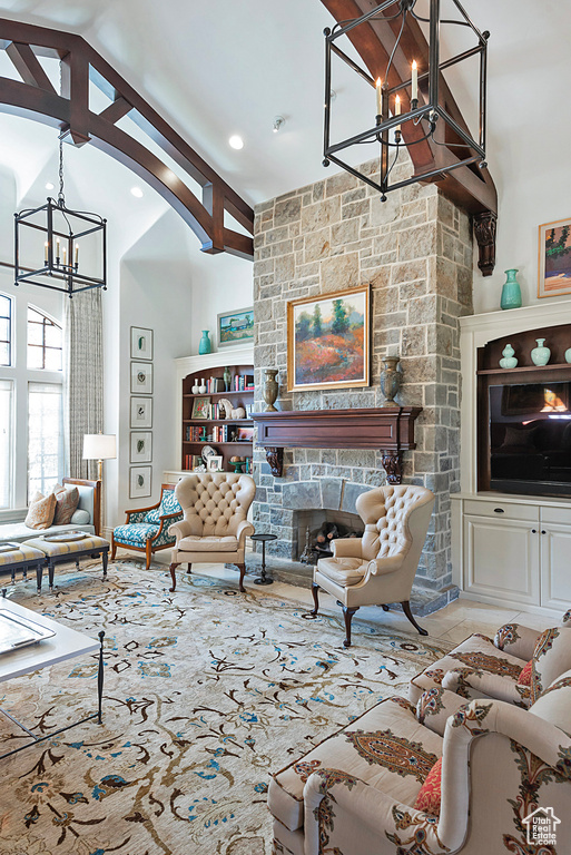 Living room with a chandelier, a stone fireplace, and high vaulted ceiling
