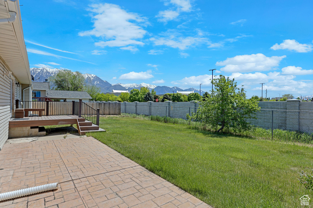 View of yard featuring a deck with mountain view and a patio area