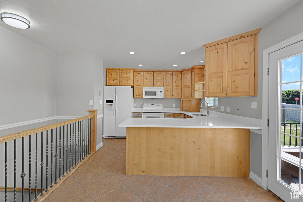 Kitchen with white appliances, a sink, light brown cabinets, light countertops, and light tile patterned floors