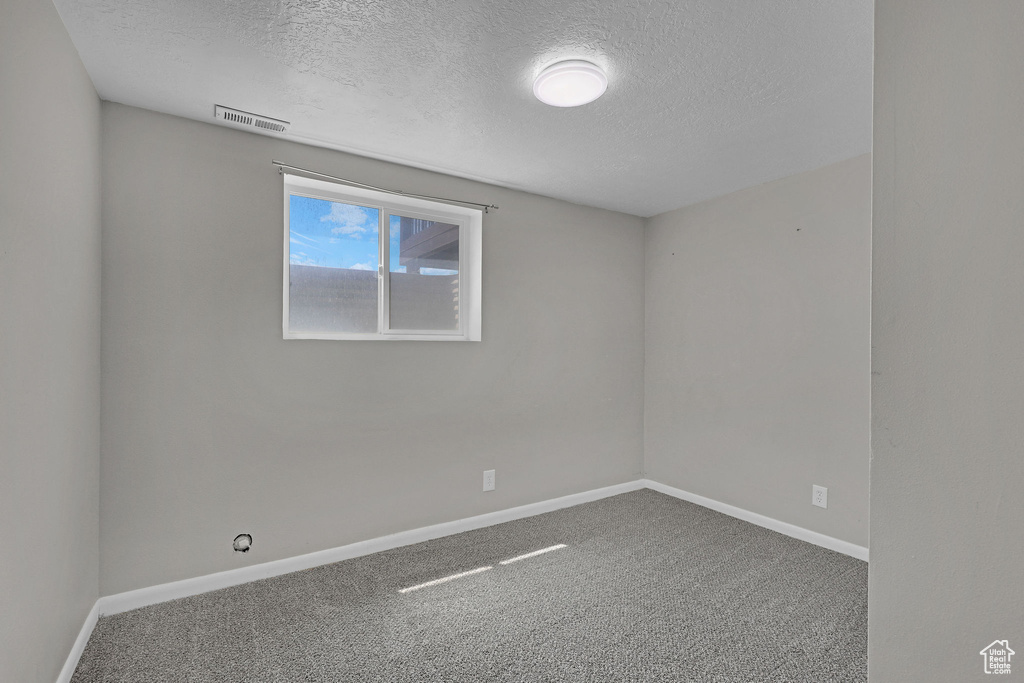 Unfurnished room with a textured ceiling, carpet, and baseboards