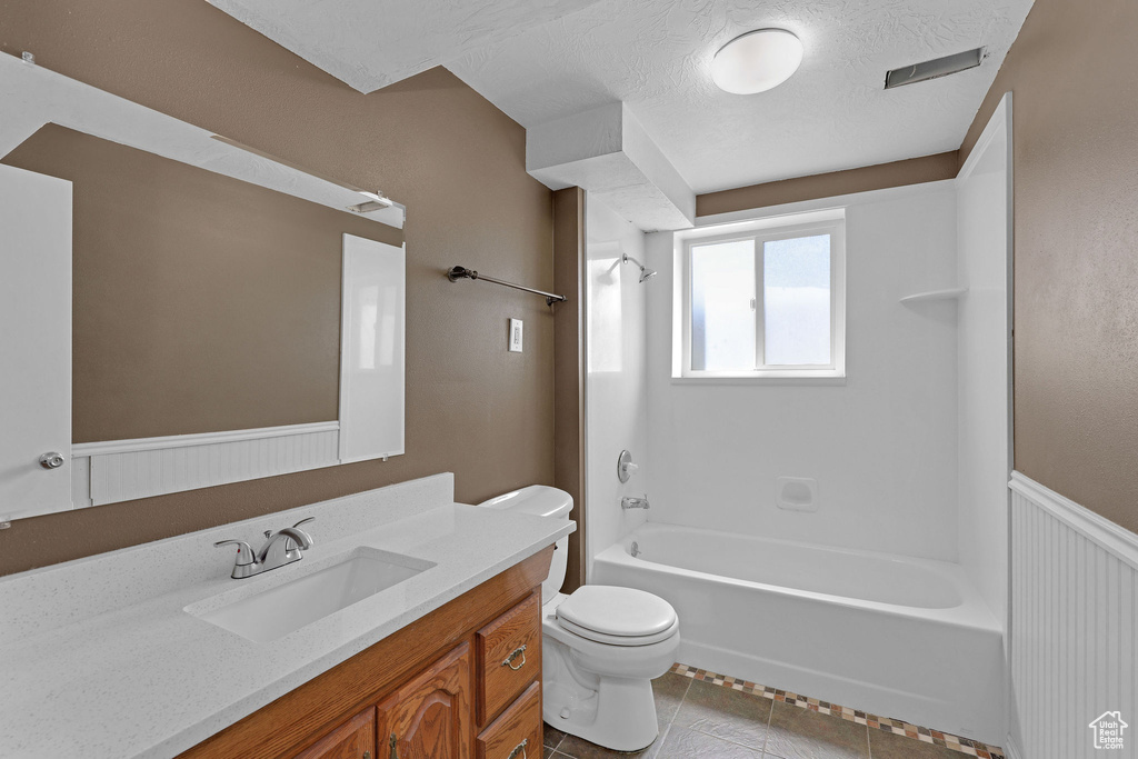 Bathroom featuring toilet, shower / washtub combination, vanity, tile patterned flooring, and a textured ceiling