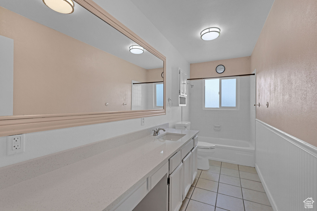 Bathroom with toilet, tile patterned floors, vanity, bathing tub / shower combination, and a wainscoted wall