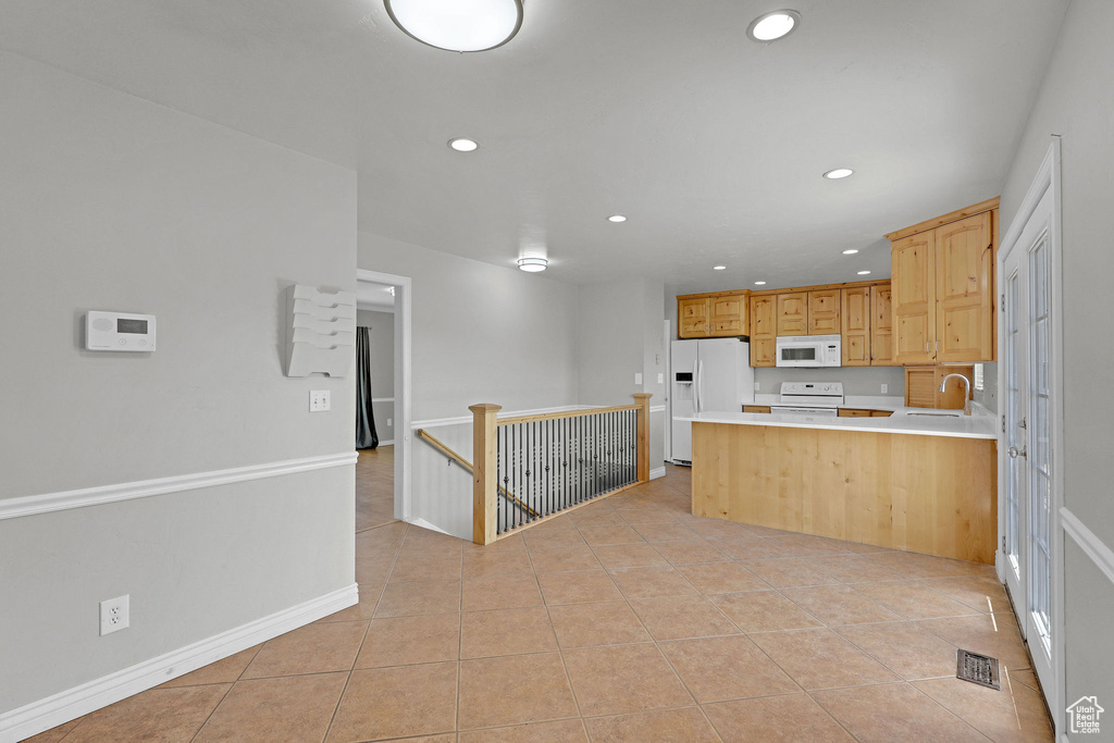 Kitchen featuring white appliances, recessed lighting, a sink, light tile patterned flooring, and a peninsula