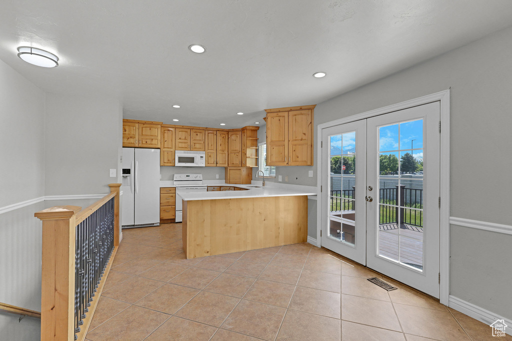 Kitchen with white appliances, french doors, a peninsula, recessed lighting, and light countertops