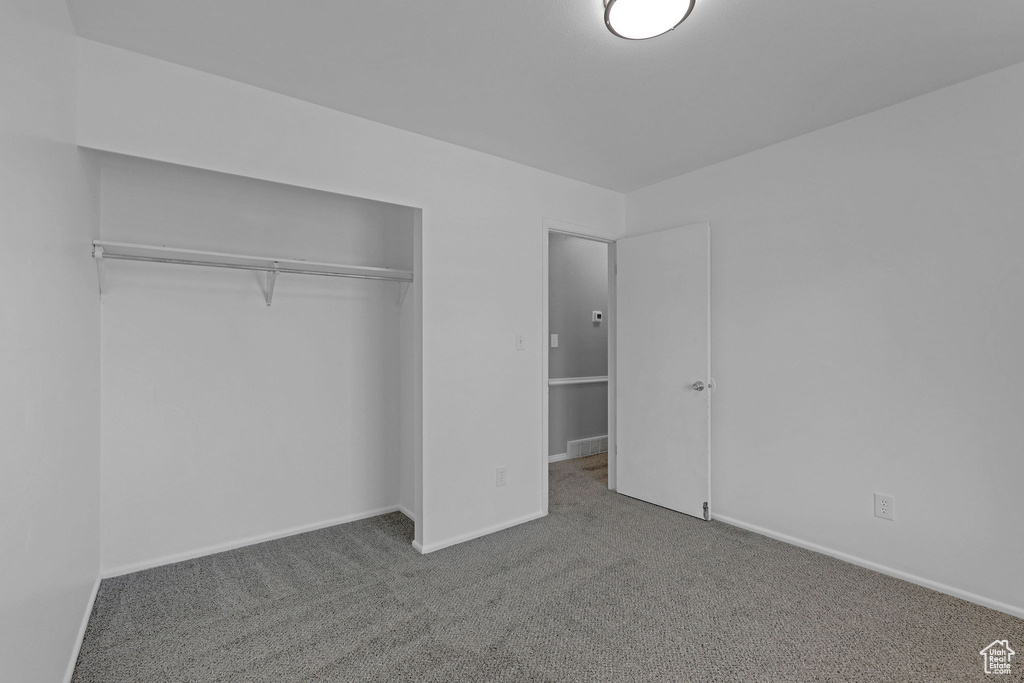 Unfurnished bedroom with carpet, a closet, and baseboards