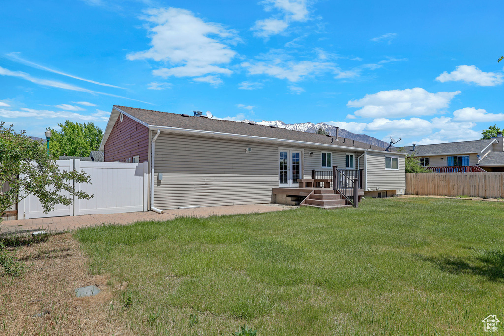 Back of house featuring a wooden deck and french doors