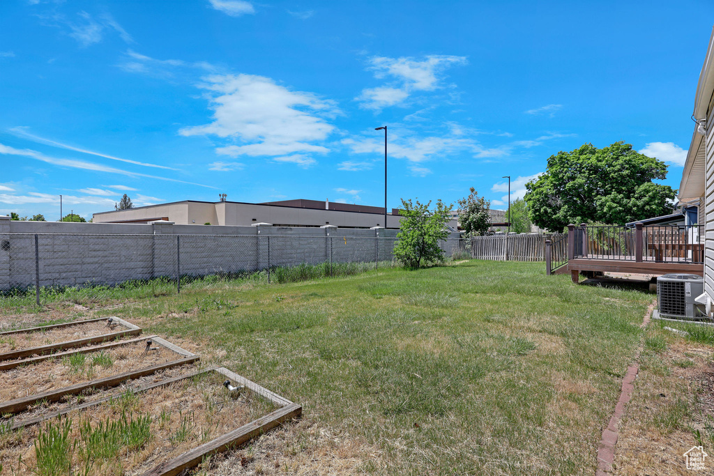 View of yard with a garden, a wooden deck, and cooling unit