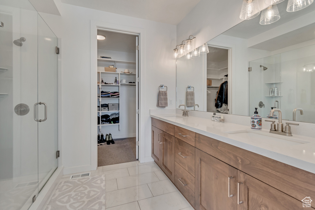 Full bath with a shower stall, double vanity, and a spacious closet