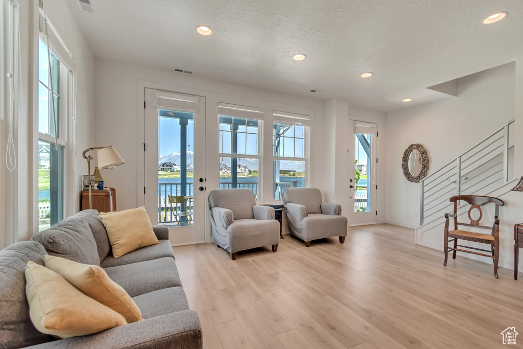 Living room with healthy amount of natural light, a water view, recessed lighting, light wood finished floors, and baseboards
