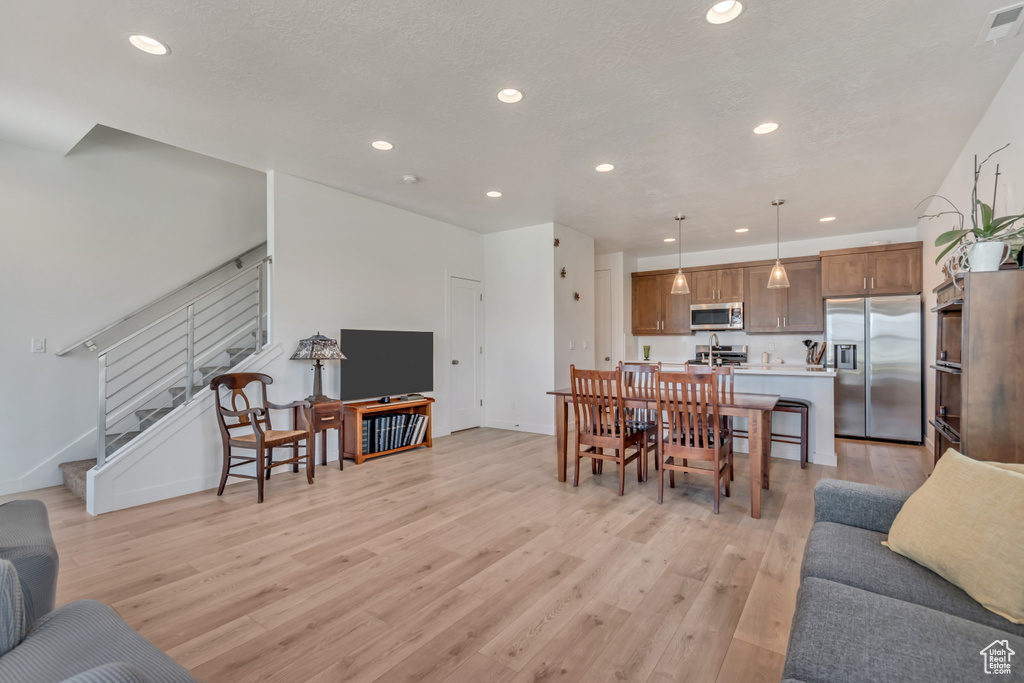 Living area with light wood finished floors, recessed lighting, and stairs