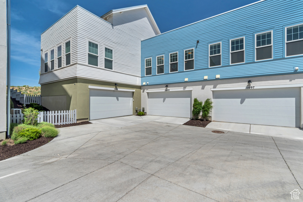 View of front facade featuring concrete driveway, fence, an attached garage, and stucco siding