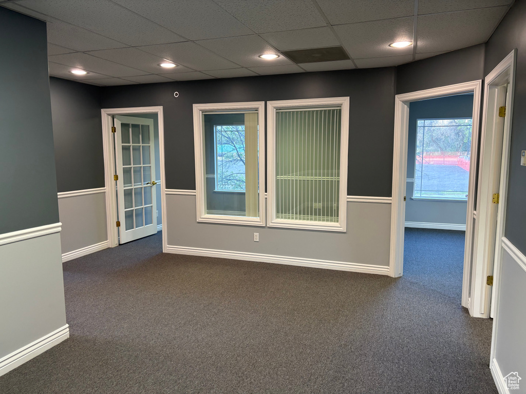Empty room featuring dark carpet, a paneled ceiling, baseboards, and recessed lighting