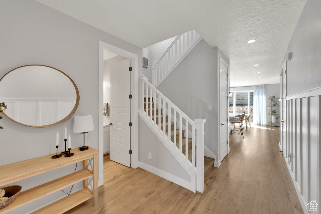 Stairs featuring wood finished floors, recessed lighting, a textured ceiling, and baseboards
