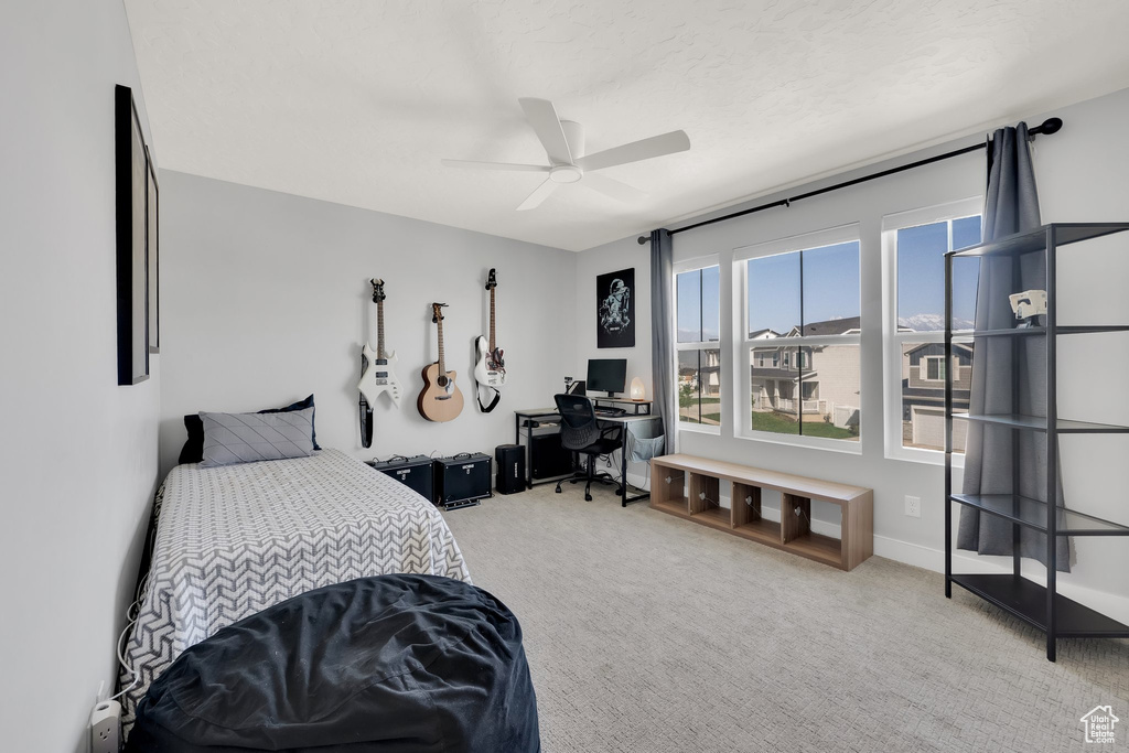 Bedroom with carpet, an office area, and a ceiling fan
