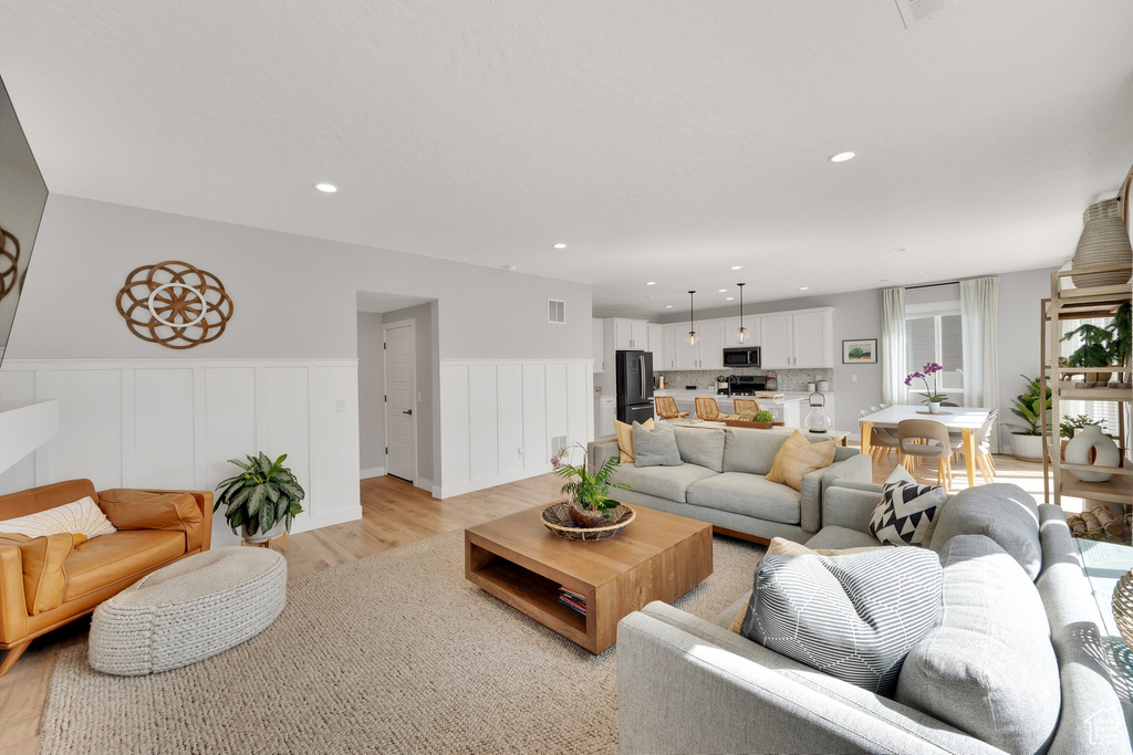 Living area with light wood-style flooring, wainscoting, and recessed lighting
