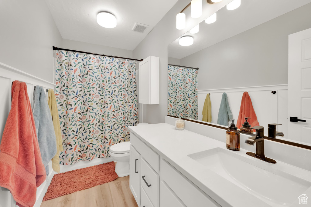 Full bath with vanity, wood finished floors, toilet, and a shower with curtain