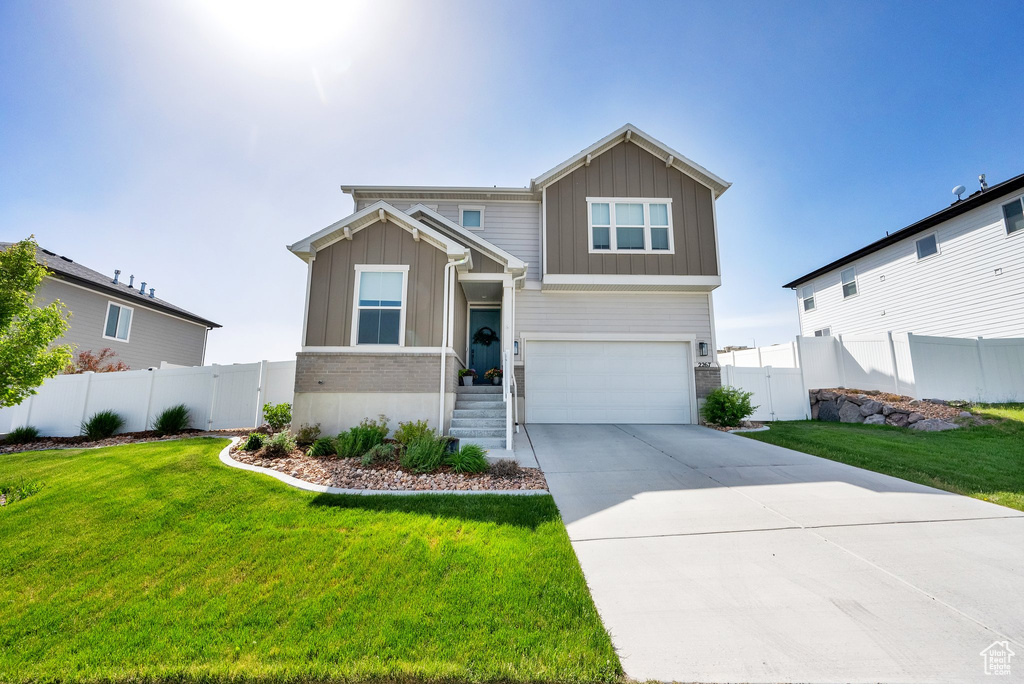 View of front of home with board and batten siding, a garage, driveway, and brick siding