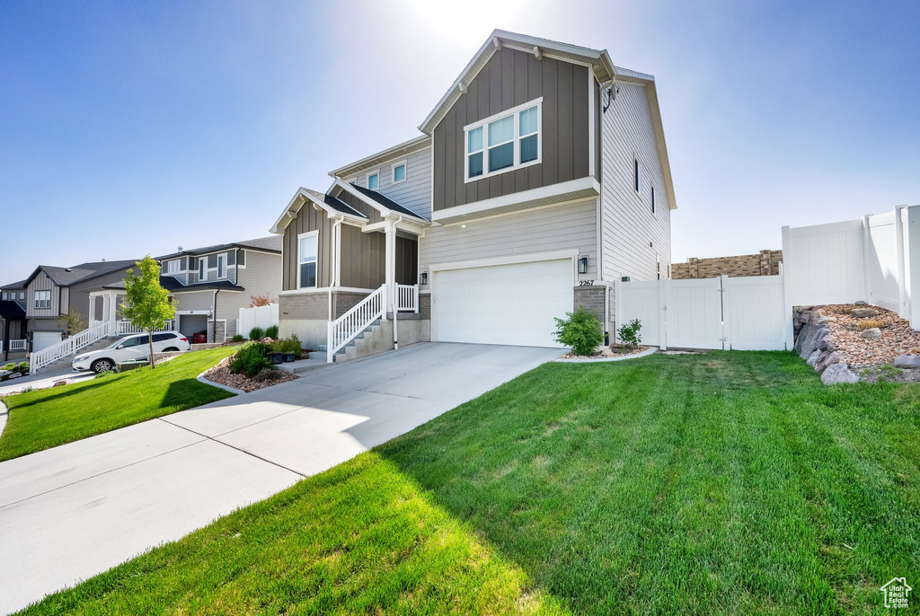 View of front facade featuring board and batten siding, an attached garage, driveway, and a residential view