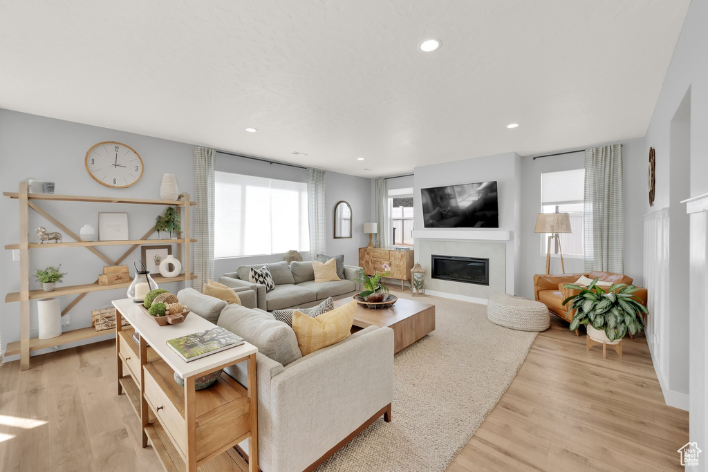 Living area with a glass covered fireplace, light wood-type flooring, recessed lighting, and baseboards