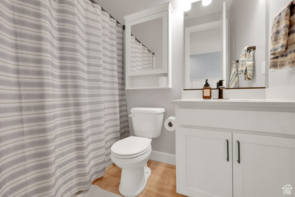 Bathroom featuring toilet, vanity, wood finished floors, and baseboards