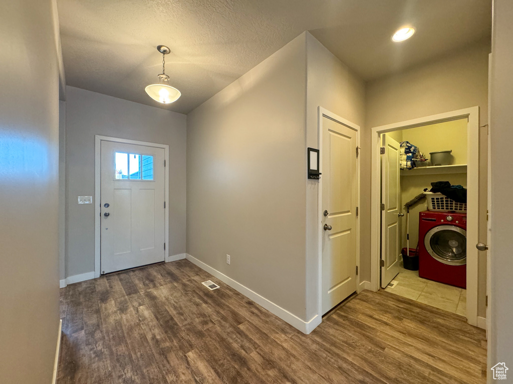 Entrance foyer with washer / dryer, wood finished floors, and baseboards