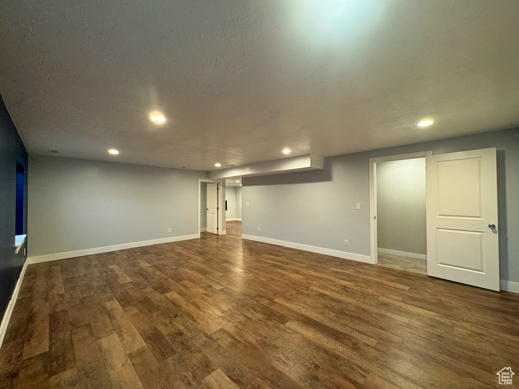 Finished below grade area featuring dark wood-type flooring, recessed lighting, baseboards, and a textured ceiling