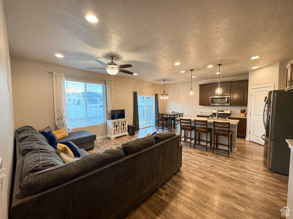 Living area with wood finished floors, recessed lighting, a textured ceiling, and ceiling fan
