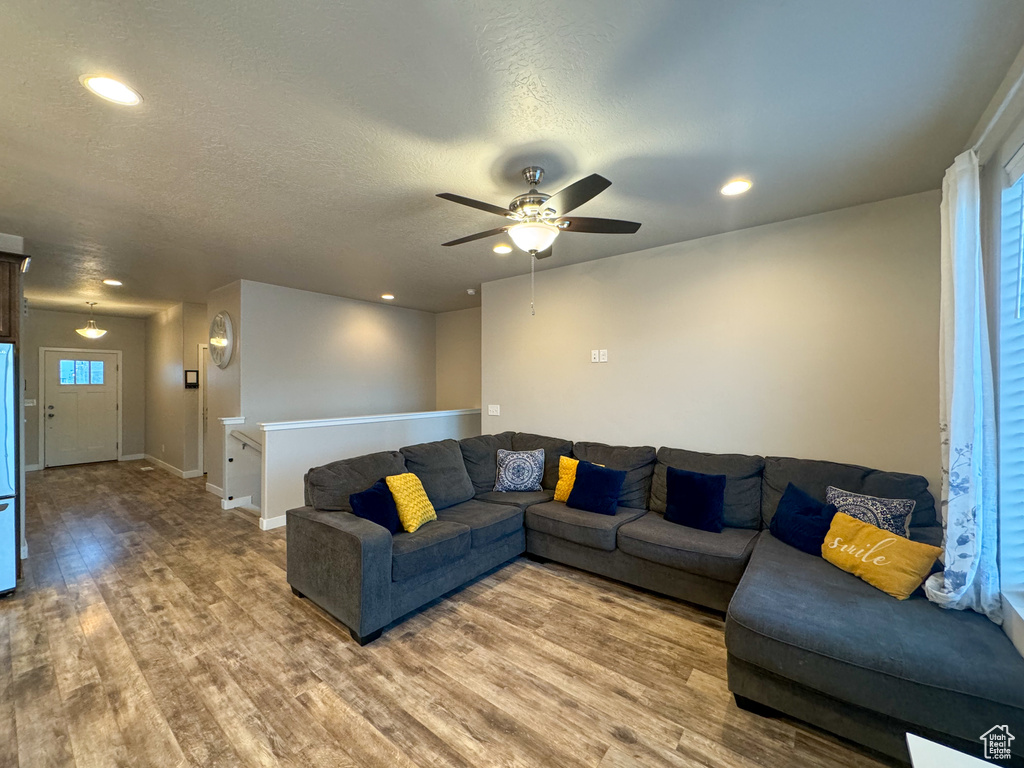 Living room with light wood-style flooring, a ceiling fan, healthy amount of natural light, recessed lighting, and a textured ceiling