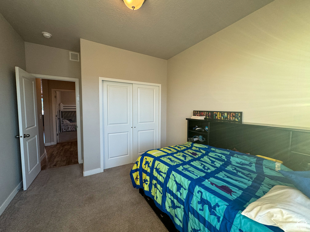 Carpeted bedroom featuring a closet and baseboards