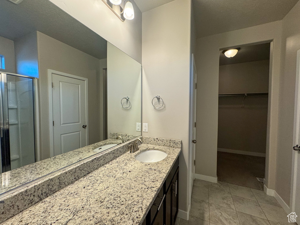 Bathroom with a stall shower, baseboards, vanity, and a spacious closet