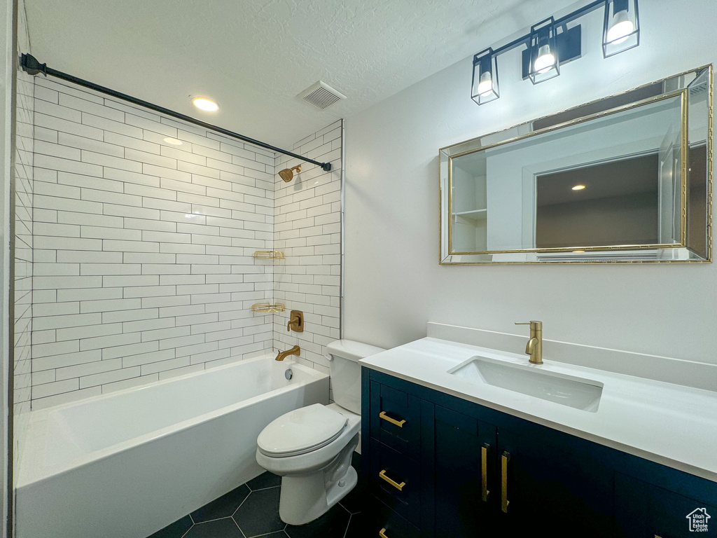 Bathroom featuring tile patterned floors, toilet, vanity, a textured ceiling, and shower / tub combination