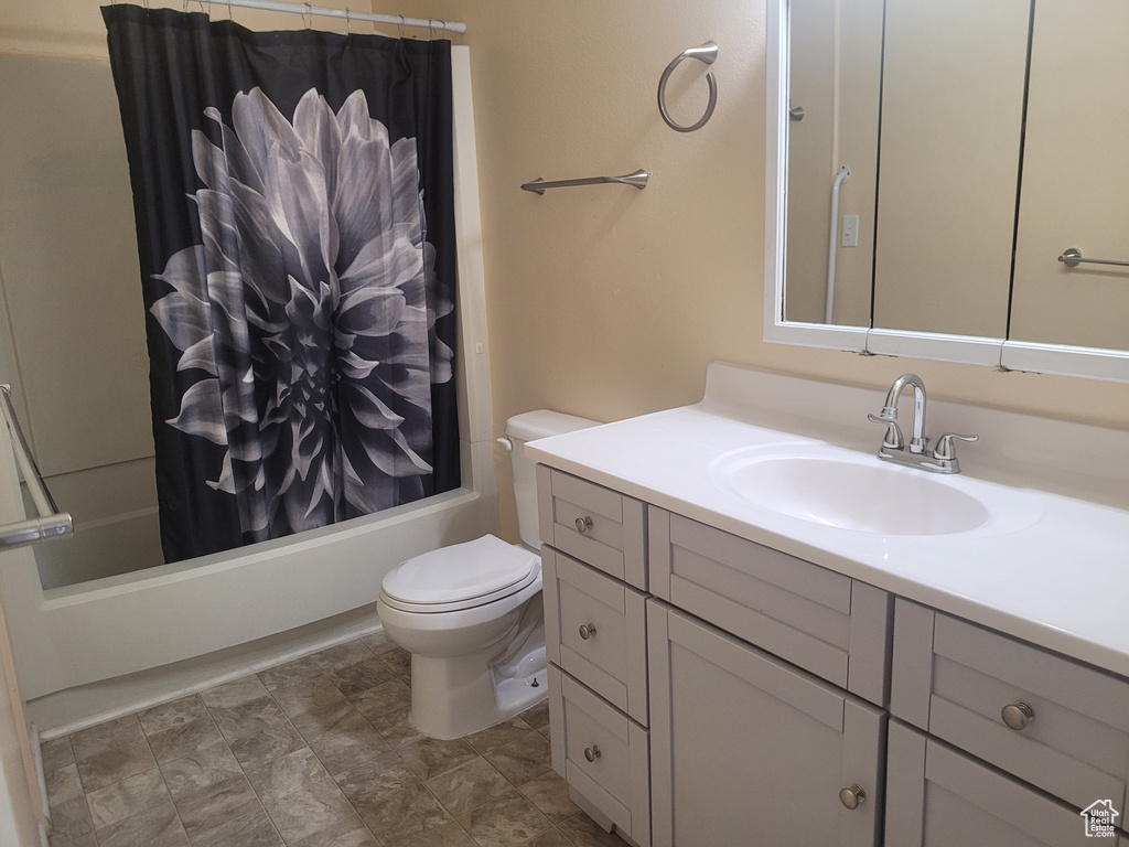 Full bathroom with vanity, toilet, and shower / bath combo with shower curtain