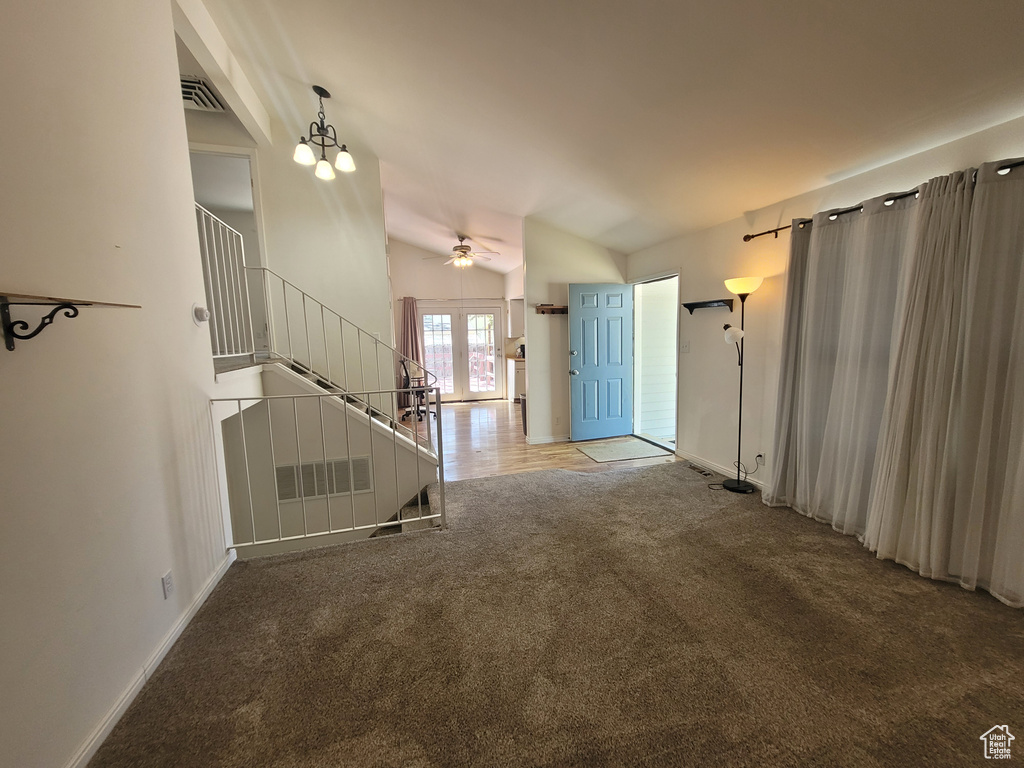 Carpeted entrance foyer with stairway, lofted ceiling, a ceiling fan, and baseboards