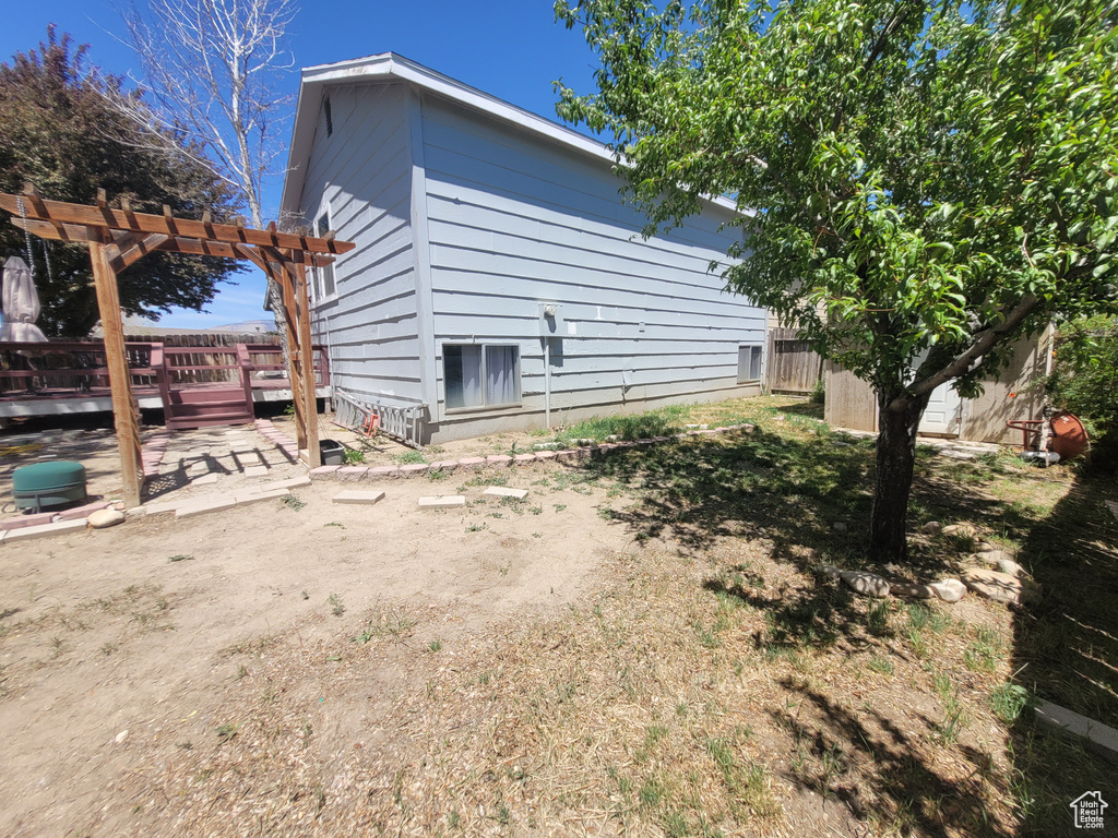 View of property exterior with a pergola and a wooden deck