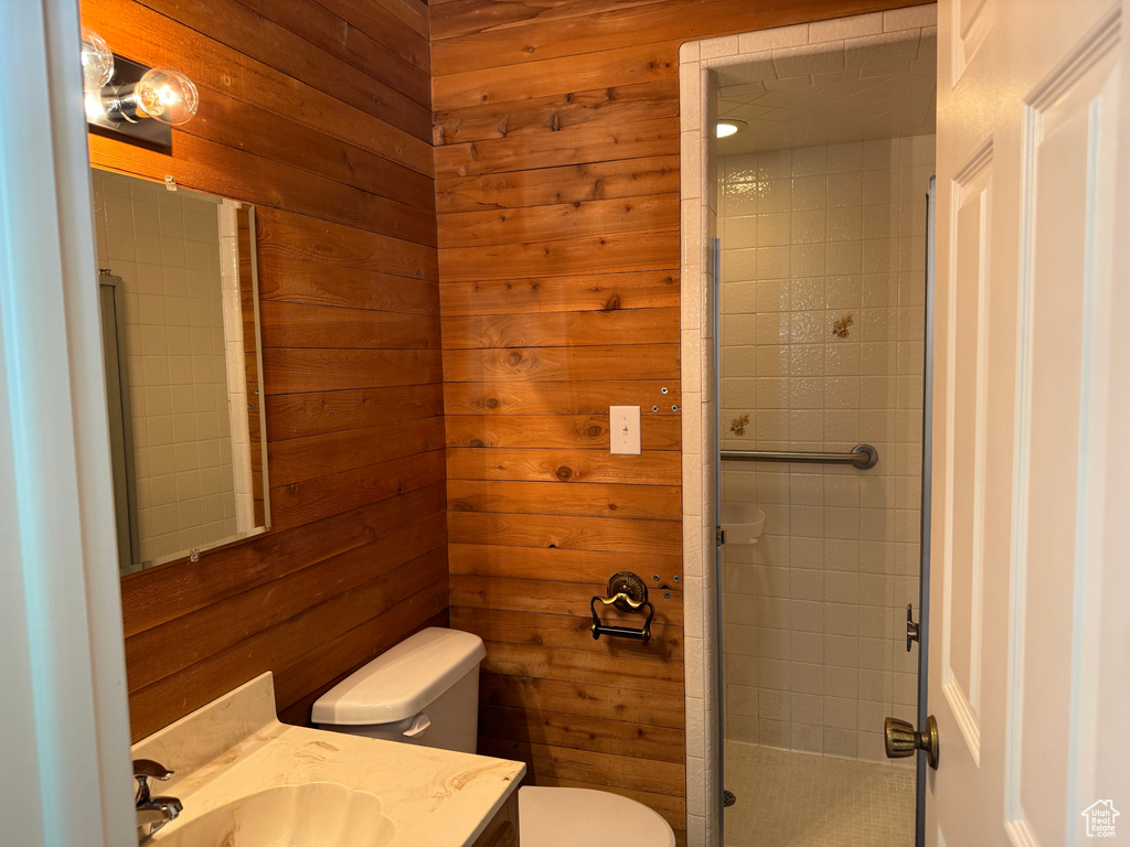 Bathroom with toilet, vanity, a shower stall, and wooden walls