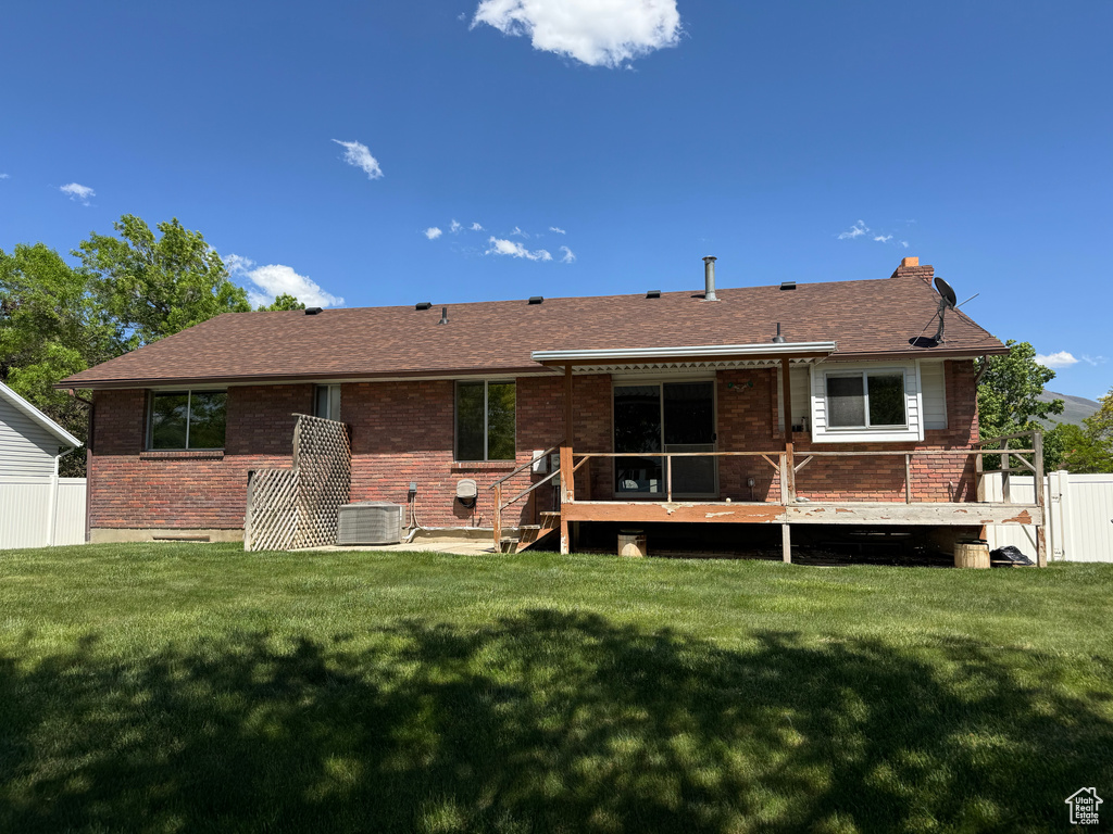Back of house featuring brick siding, a deck, central air condition unit, and a shingled roof