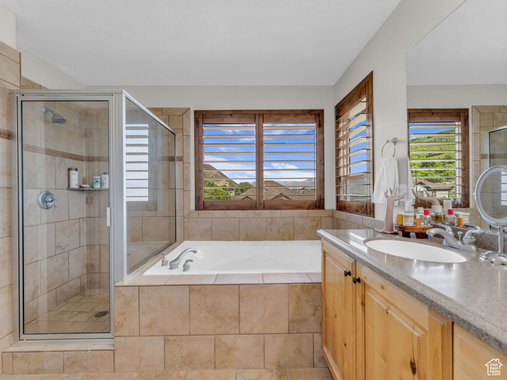 Bathroom featuring a shower stall, a bath, and vanity