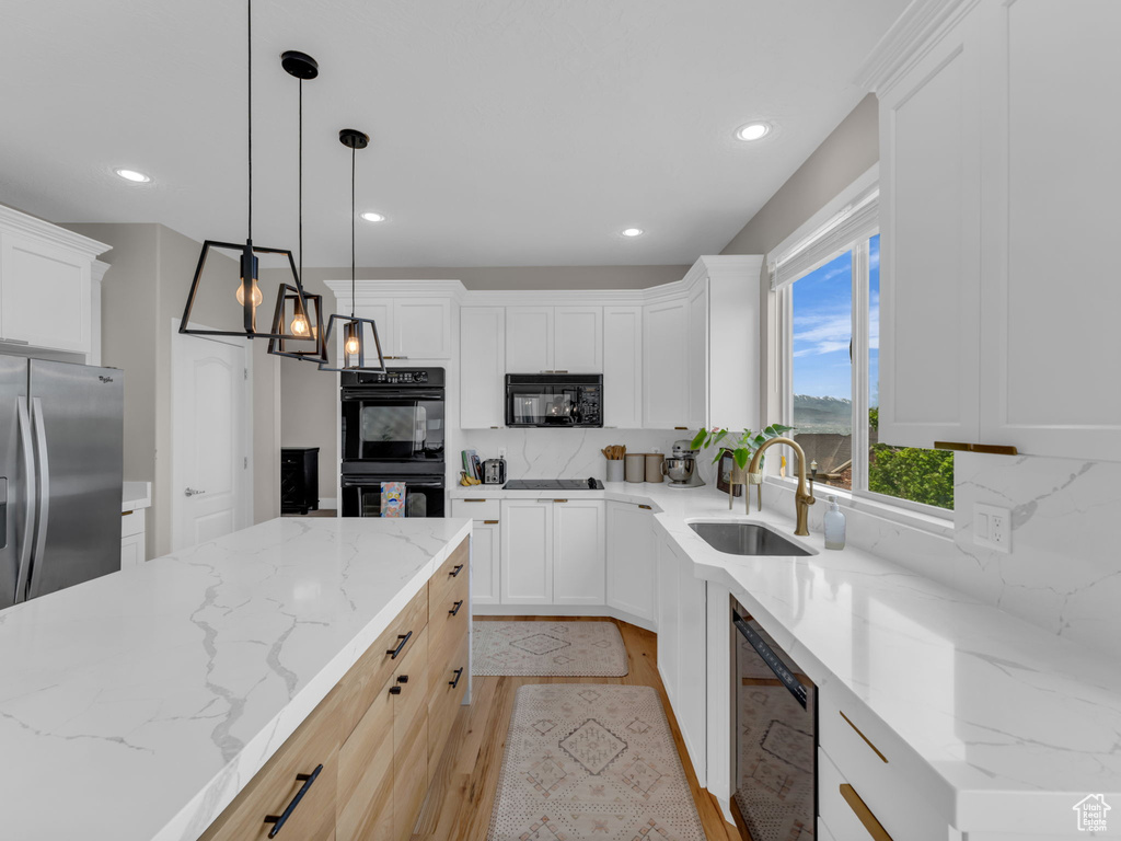 Kitchen featuring a sink, black appliances, light wood-type flooring, decorative backsplash, and recessed lighting