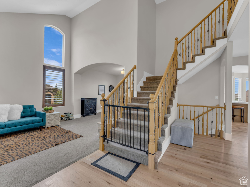 Stairway featuring high vaulted ceiling, arched walkways, wood finished floors, and baseboards