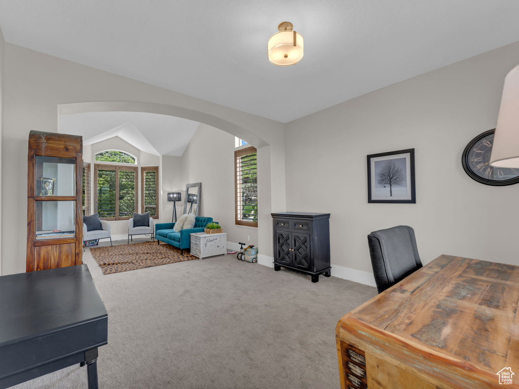 Carpeted office with arched walkways, baseboards, and lofted ceiling