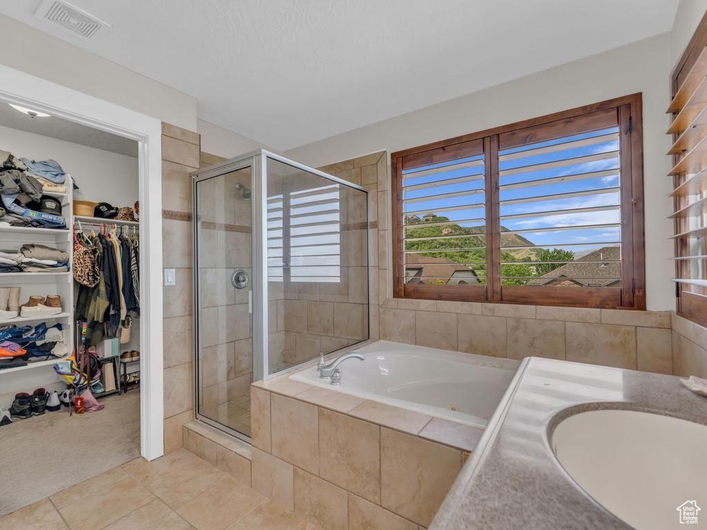 Bathroom featuring a stall shower, tile patterned flooring, a walk in closet, and a bath