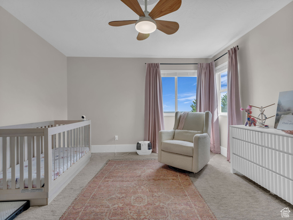 Bedroom with baseboards, a nursery area, carpet floors, and ceiling fan