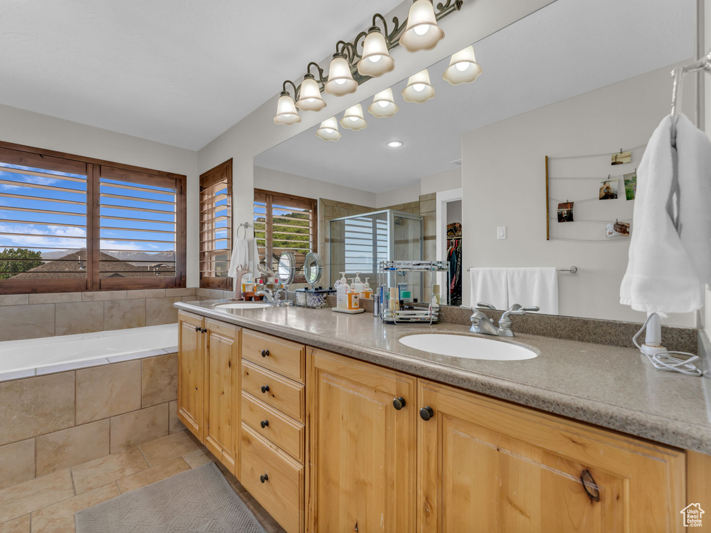 Bathroom featuring a shower stall, double vanity, and a garden tub