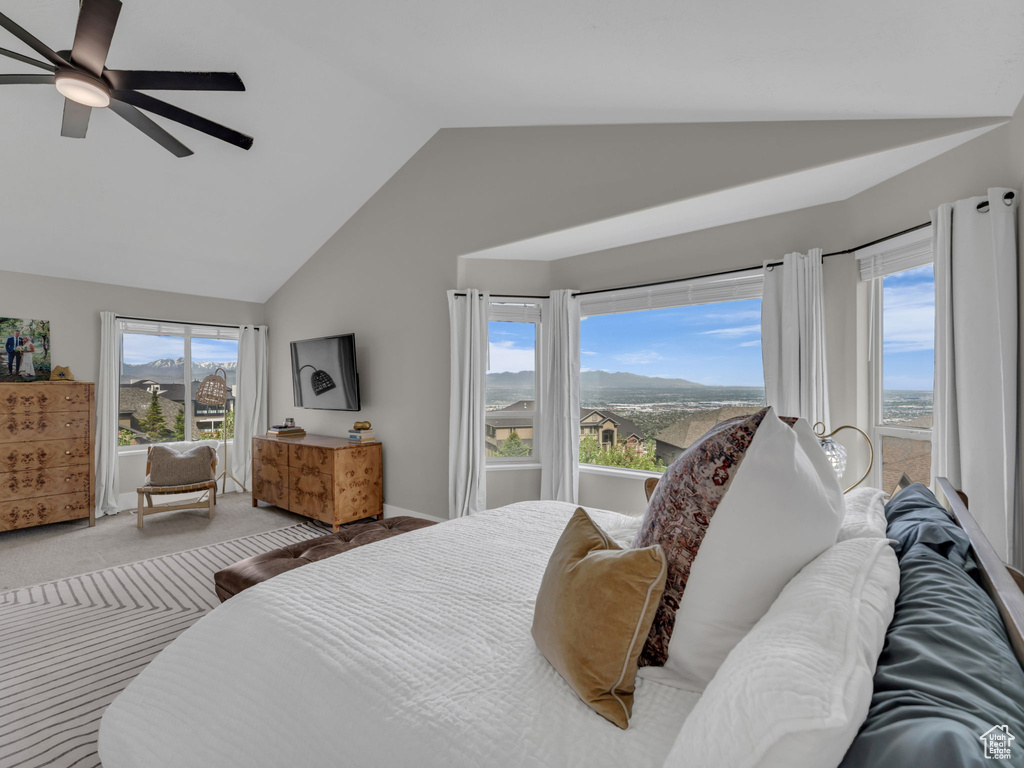Carpeted bedroom featuring vaulted ceiling and a ceiling fan